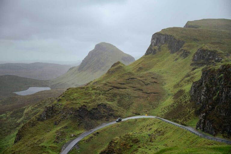 car driving on winding road through green Scottish mountains